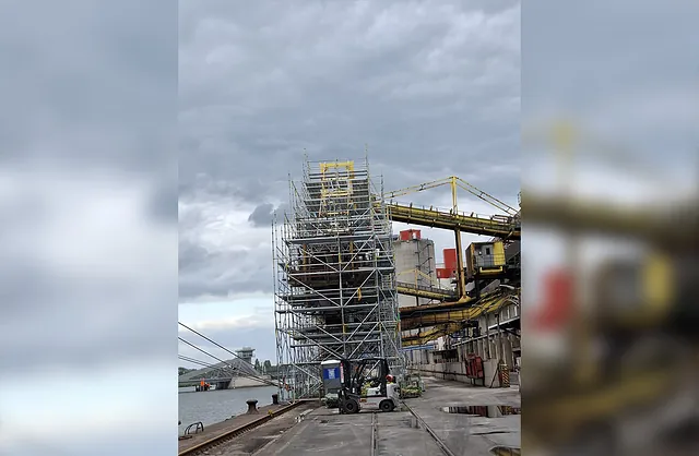 Hohes Industriegerüst rund um eine Förderanlage im Hafen mit mehreren Arbeitsebenen für Wartungsarbeiten und industrielle Instandhaltung.