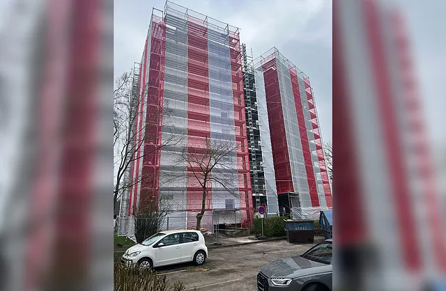 Zwei hohe Gebäudeteile mit mehrstöckigen Fassadengerüsten und rot-weißen Schutznetzen für Sanierungsarbeiten in Hamburg-Rahlstedt.