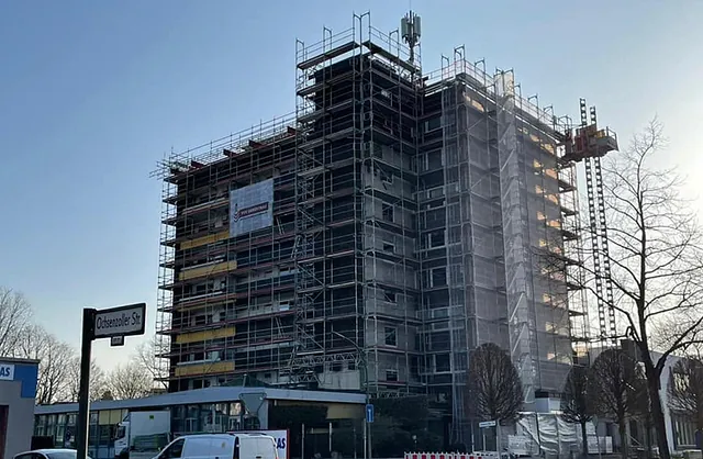 Hochhaus mit umlaufendem Fassadengerüst, Gerüstaufzug und Schutznetzen für Gebäudesanierungen an der Ochsenzollerstraße in Norderstedt.