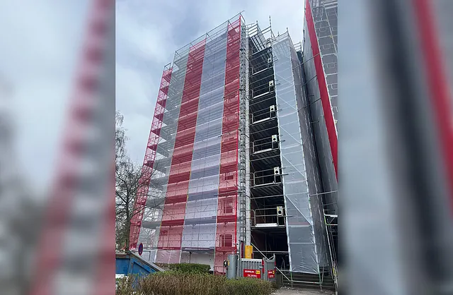 Mehrstöckiges Fassadengerüst mit rot-weißen Schutznetzen und Gerüstaufzug an einem Gebäude in der Friedrichshainstraße 8 in Hamburg.