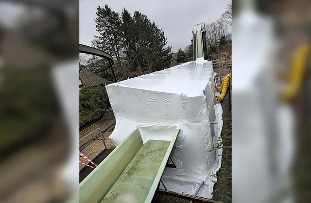 Blick von oben auf die weiß eingehauste Wasserbahn im Heide Park Soltau mit Gerüstkonstruktion für Wartungs- und Sanierungsarbeiten.