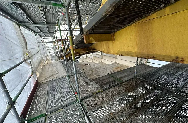 Mehrgeschossiges Industriegerüst mit Arbeitsplattformen unter einer großen Stahlträgerkonstruktion für anspruchsvolle Montagearbeiten.